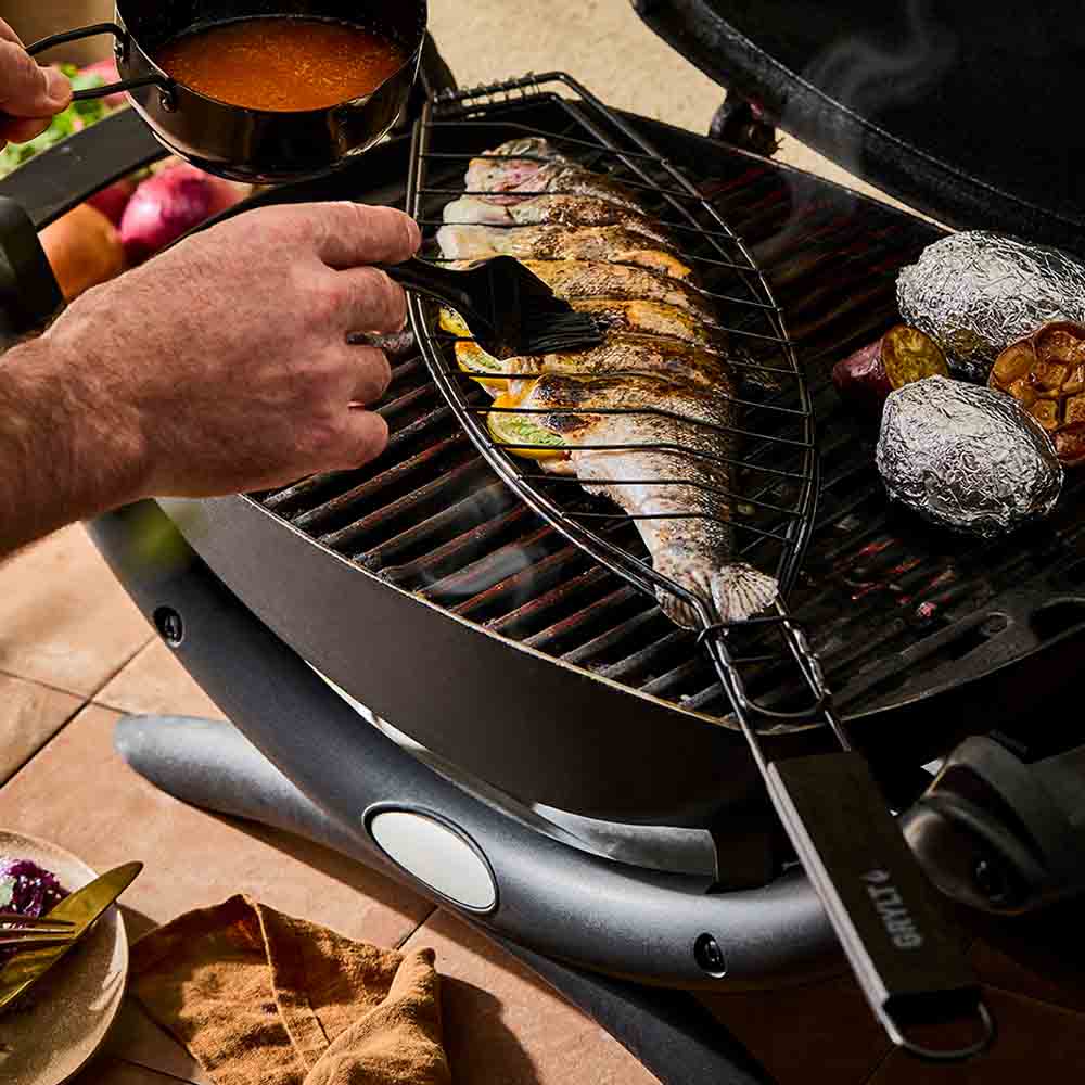 man basting sauce onto a fish on the BBQ - MyHouse