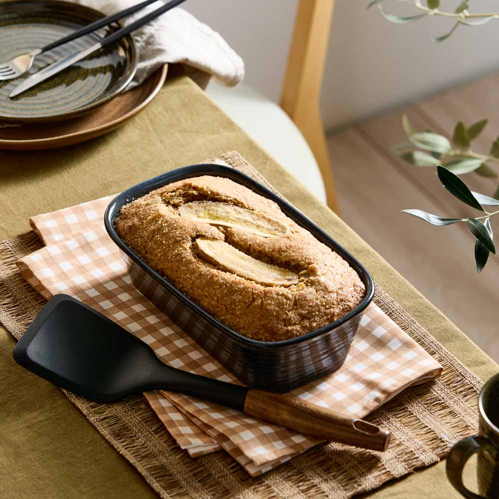 banana bread loaf in a navy blue loaf pan on a table with check tea towel _ MyHouse