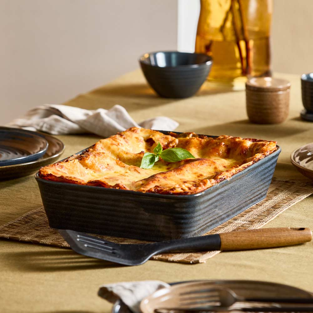 baked lasagne in navy lasagne dish sitting a table - MyHouse