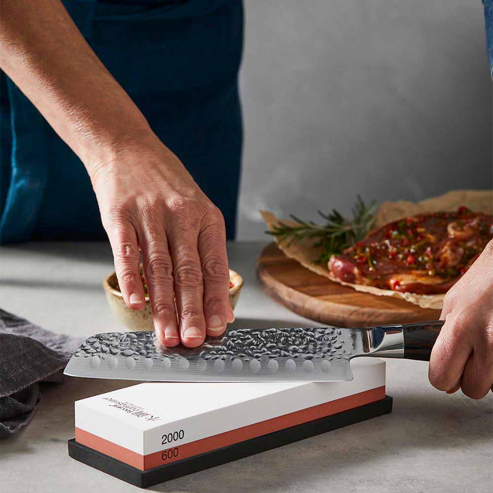 woman sharpening knife using a whetstone - MyHouse
