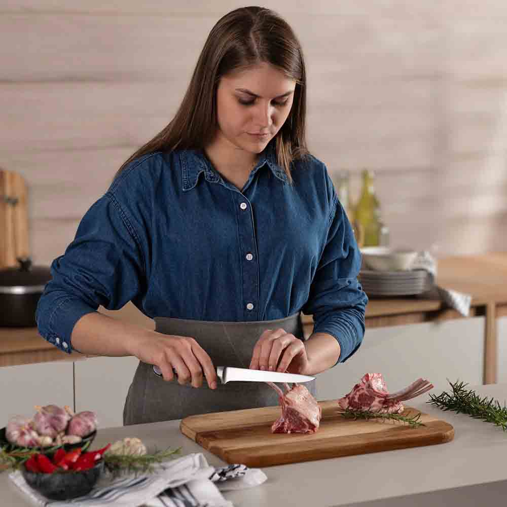 woman frenching rack of lamb with boning knife - MyHouse