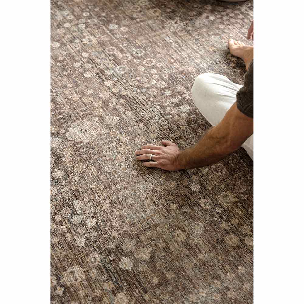Darren Palmer Moorland Rug in Fig with Darren Palmer sitting on a rug at MyHouse