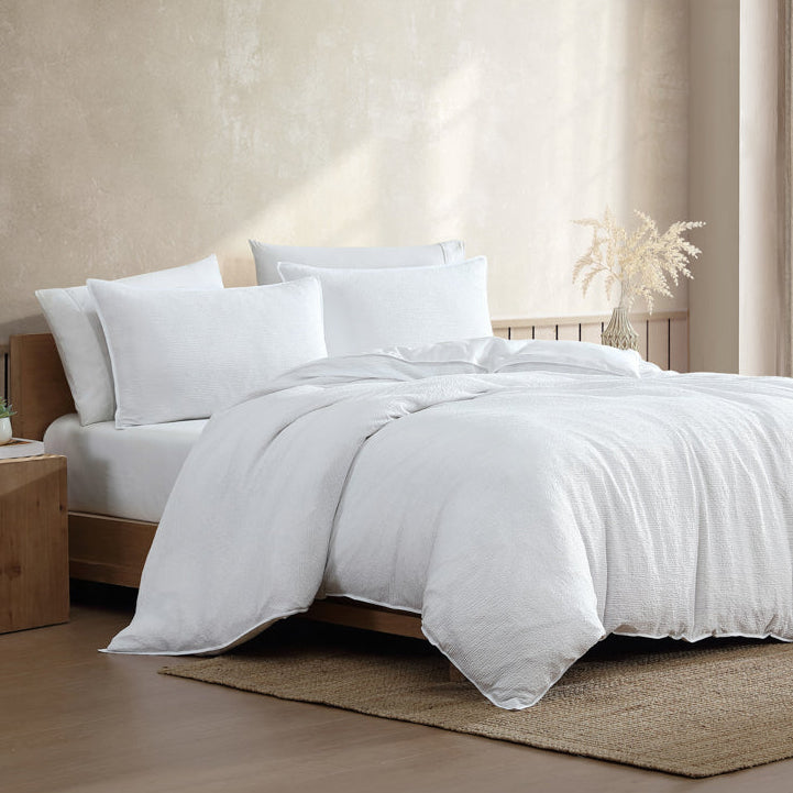 White bedding set on a bed in a bedroom with neutral decor