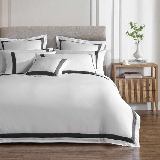 A quilt cover set with white cotton fabric accented with charcoal and sage embroidery, displayed on a bed in an elegant bedroom setting.