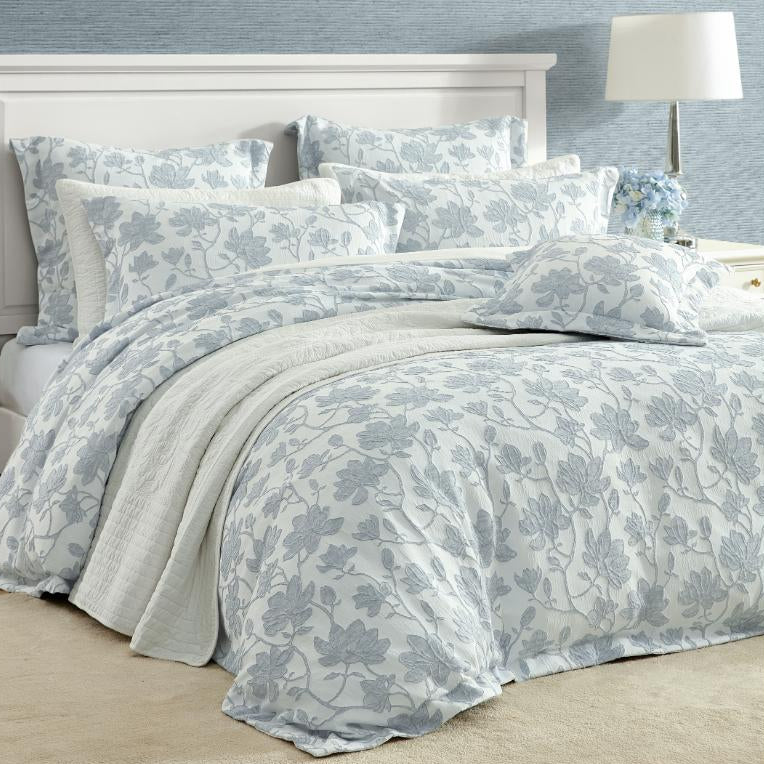Floral patterned bedding set on a bed with a lamp in the background.