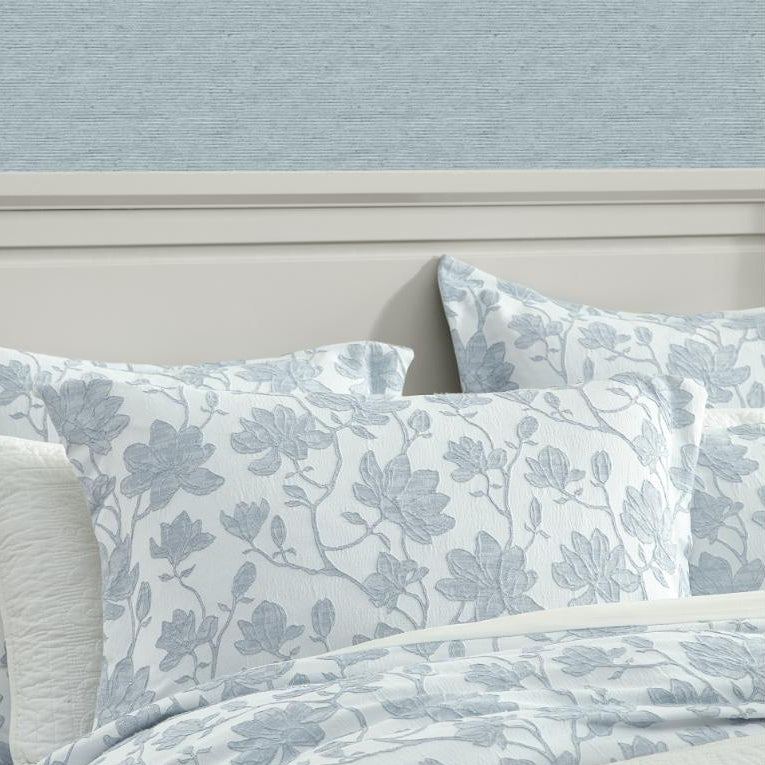 Floral patterned bedding set on a bed with a light blue wall in the background