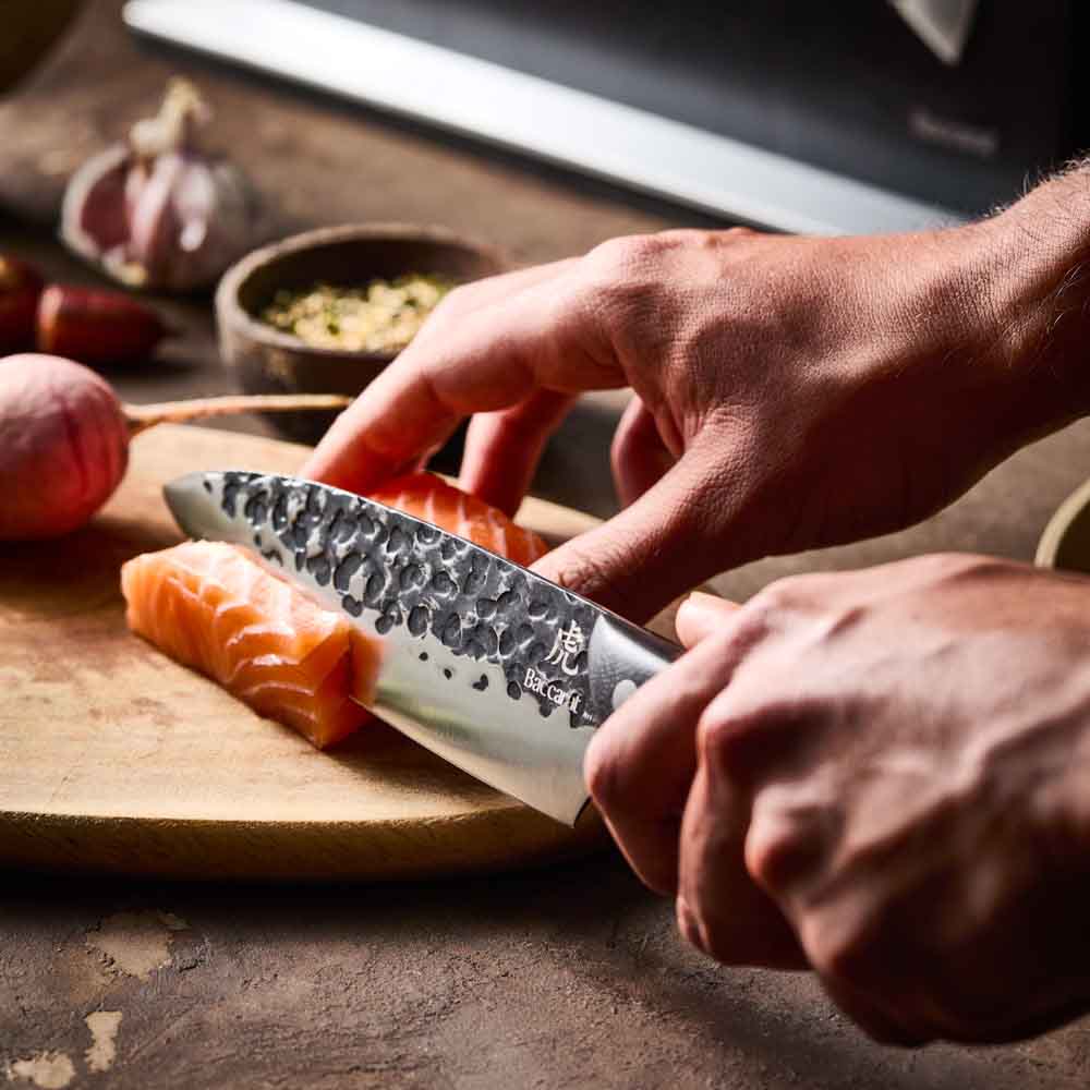 Man slicing salmon with Baccarat KUROI KIBA 7 Piece Knife Block at MyHouse