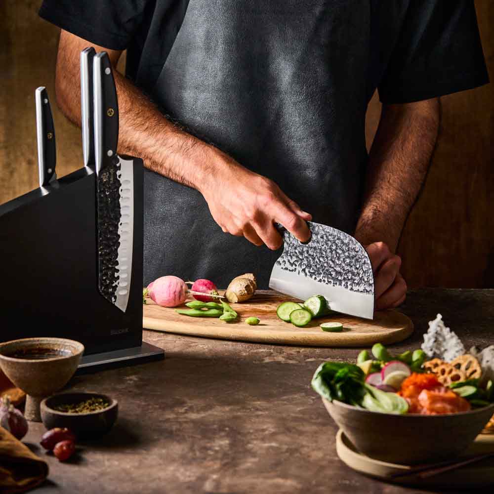 Man slicing cucumber with Baccarat KUROI KIBA 7 Piece Knife Block at MyHouse