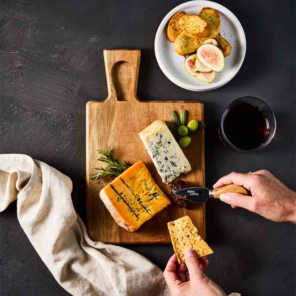 person cutting into quince paste on cheese board with knife - MyHouse