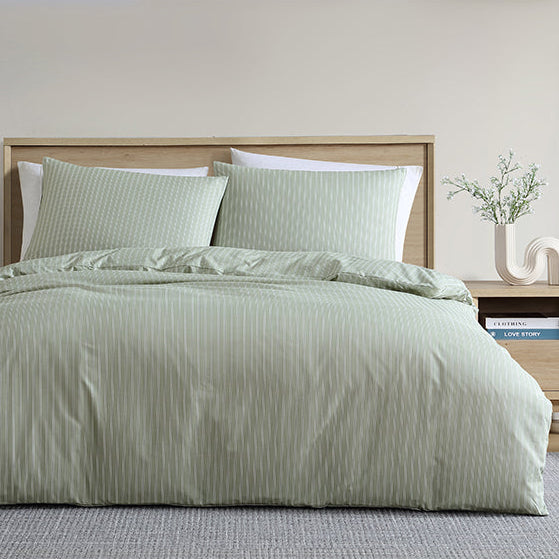 Bedroom with a bed featuring green bedding and pillows, nightstands with lamps, and decorative elements.